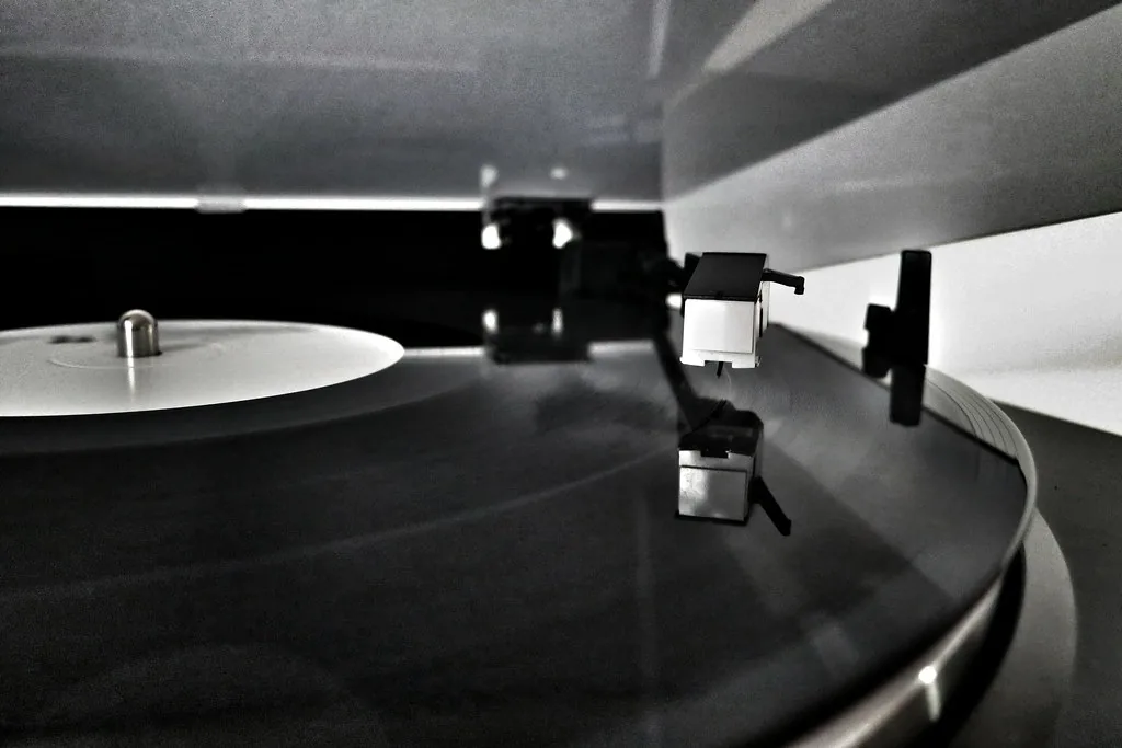 A turntable platter and tonearm in black and white